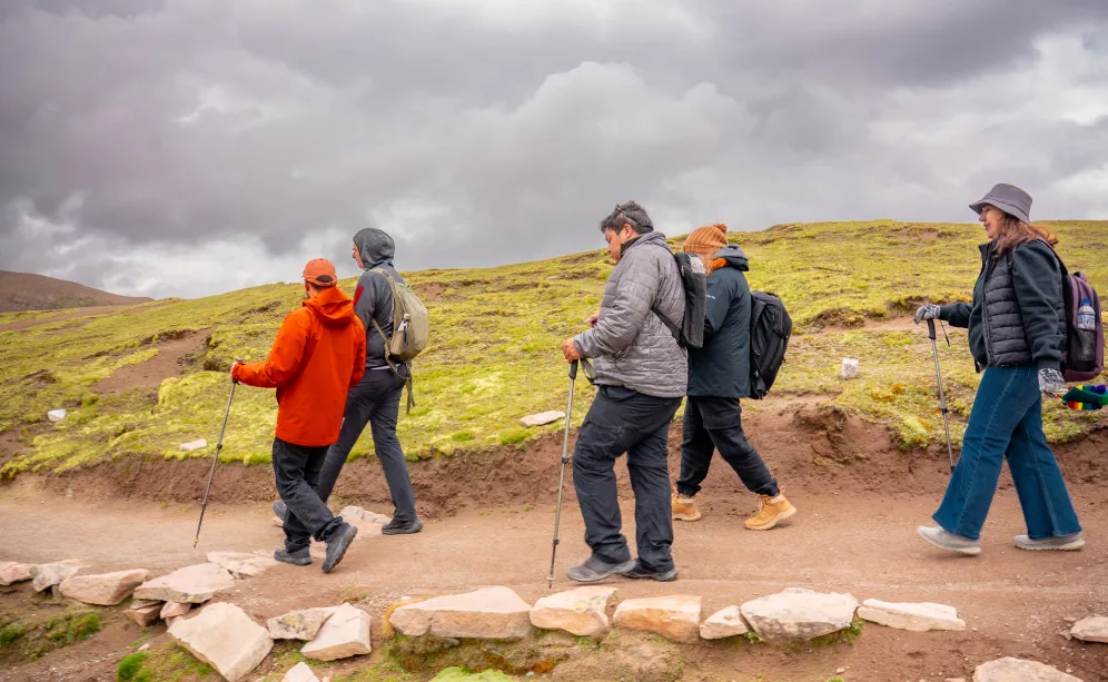 Grupo de viajeros caminando con bastones y ropa adecuada para la Montaña de Colores 