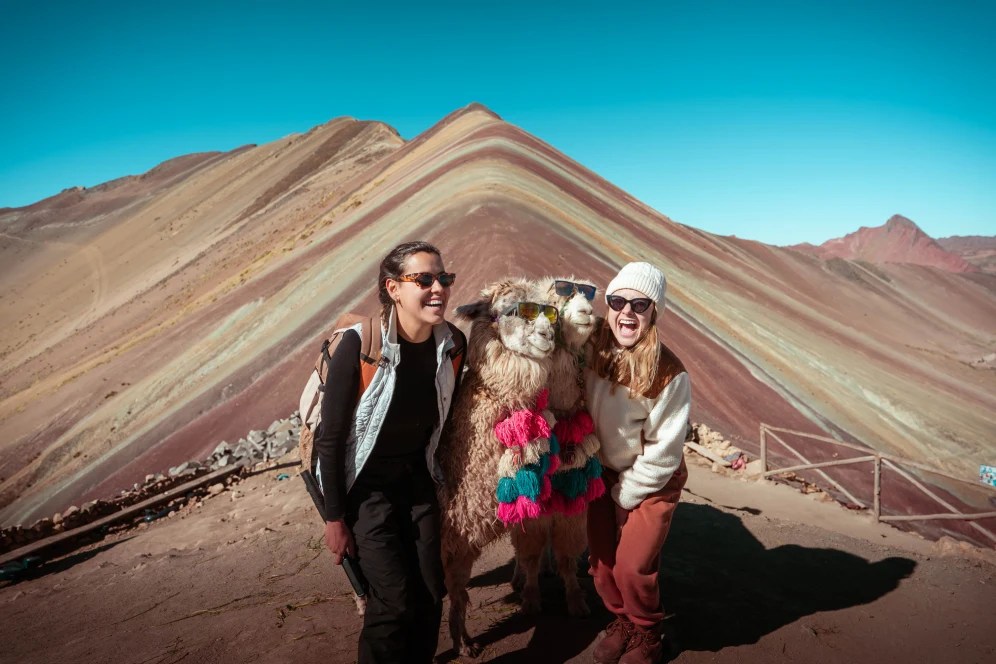 Travelers smiling at Vinicunca Rainbow Mountain in Cusco with colorful mineral stripes in the background